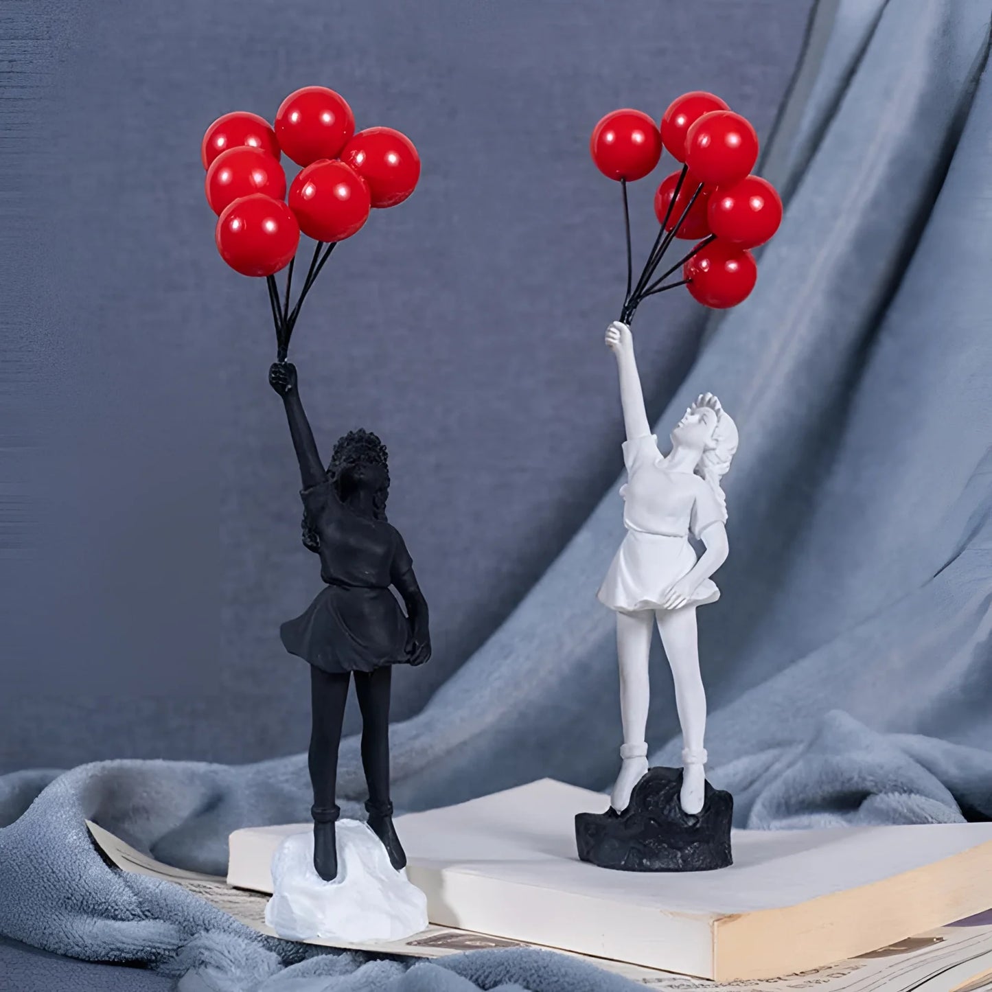 
A white resin statuette depicting a girl with a joyous gesture, holding a red heart-shaped balloon. The design is inspired by urban art, making it a unique piece for décor.