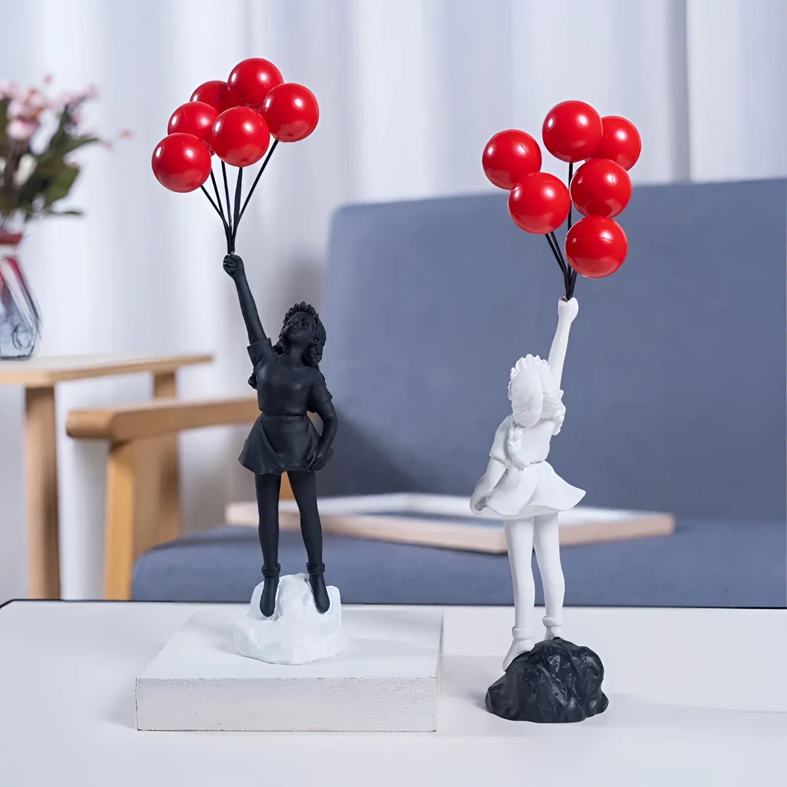 Urban art-inspired resin statuette depicting a girl holding a red balloon, dressed in a white dress, standing amidst decorative elements resembling petals and stylized plant forms.