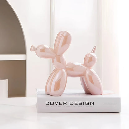 Pink metallic balloon dog sculpture on a wooden surface, serving as contemporary art decor.