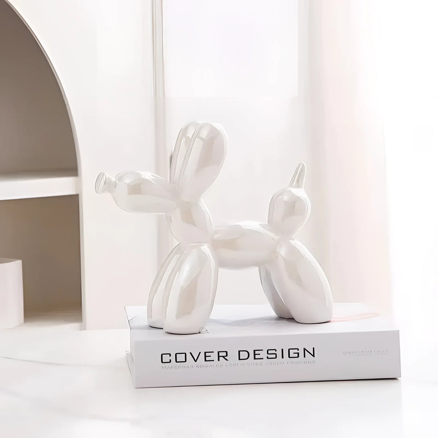 Silver balloon dog sculpture with a metallic finish, styled as contemporary art decor in a white variant, placed against a neutral beige background.